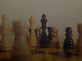 Dramatic shot of a chess board, with the foreground peices out of focus, with a white queen in front of a black king