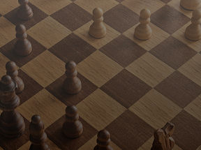 A wooden chessboard with only a few pieces left on it.